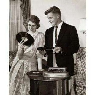 Young couple holding records near turntable Poster Print (18 x 24)