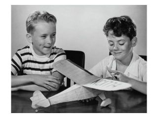 Boy making a model airplane and another boy sitting beside him Poster Print (18 x 24)
